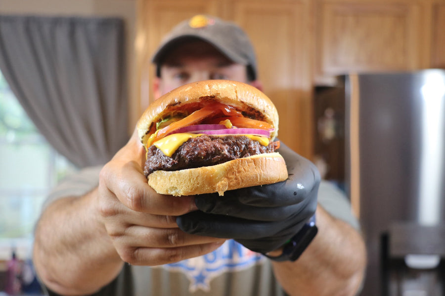 Finished homemade grilled cheeseburger held toward the camera
